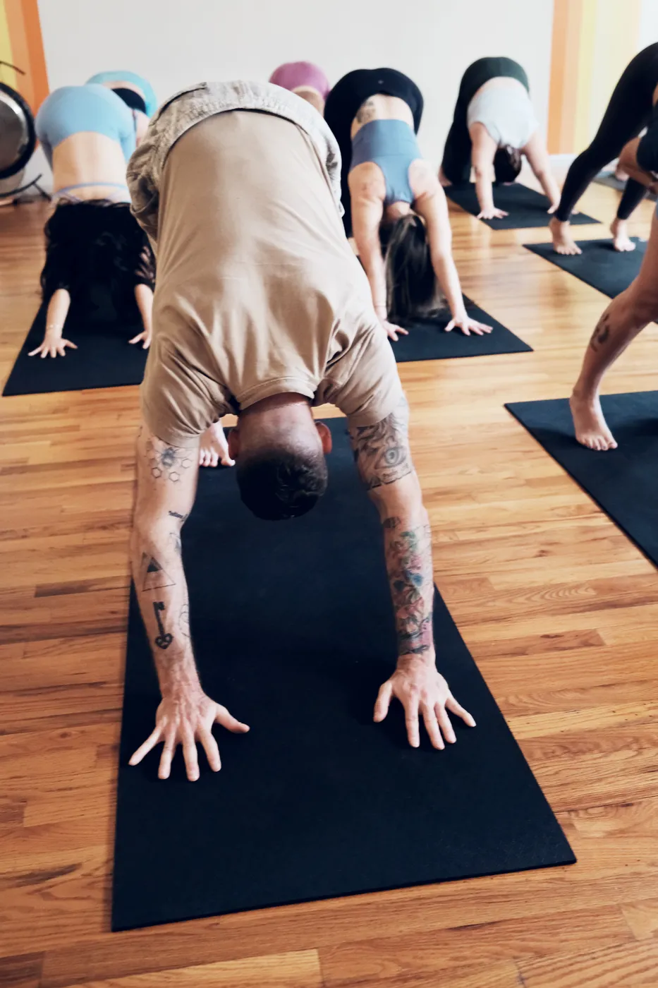 A student holding downward dog on a black mat