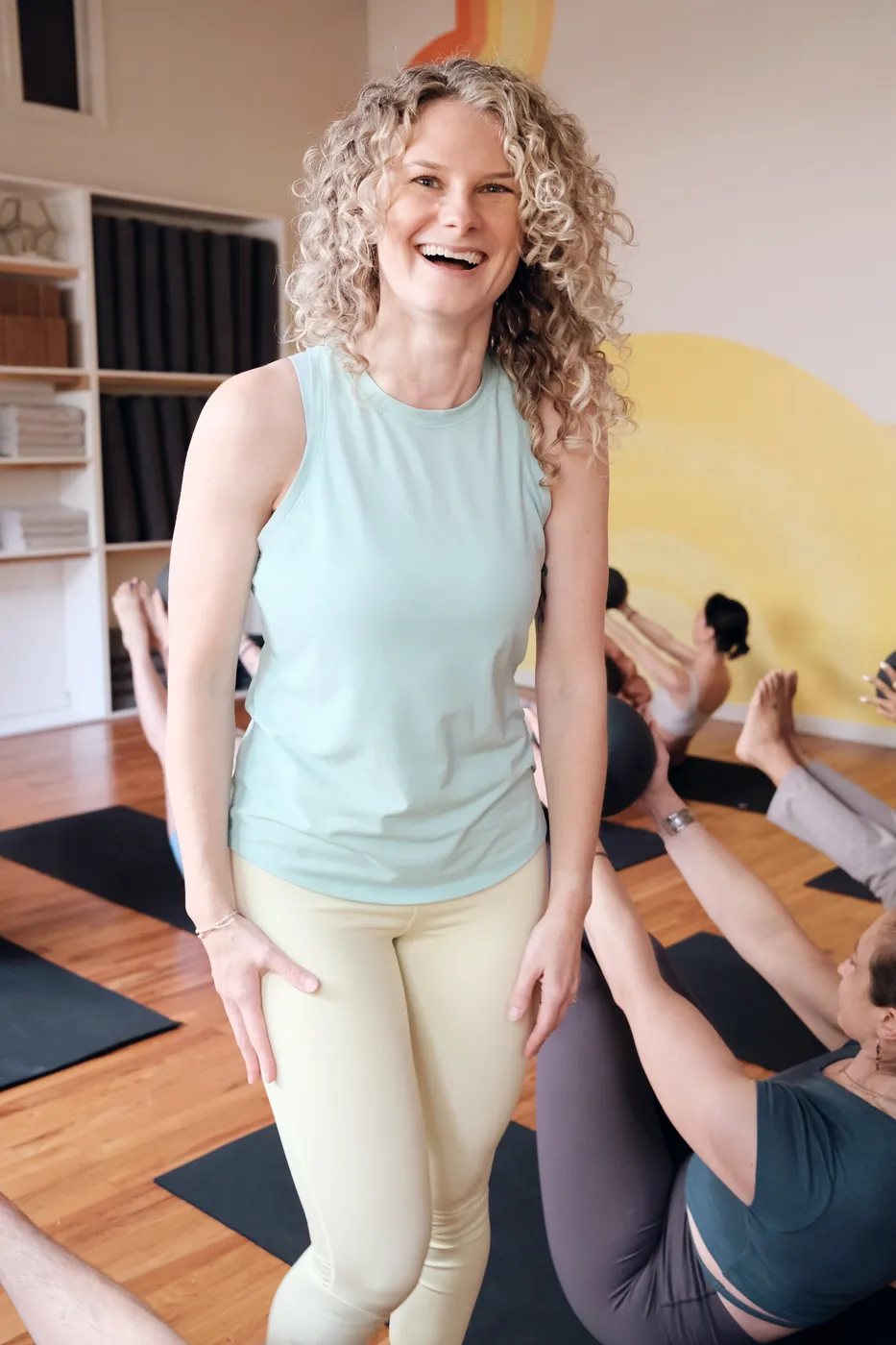 A smiling teacher walking between students' mats
