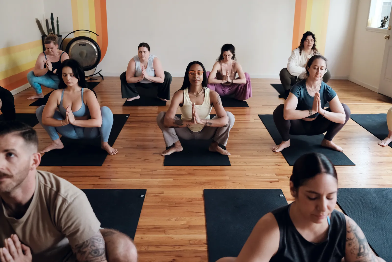 A full class seated in meditation, gongs set up at the back of the studio